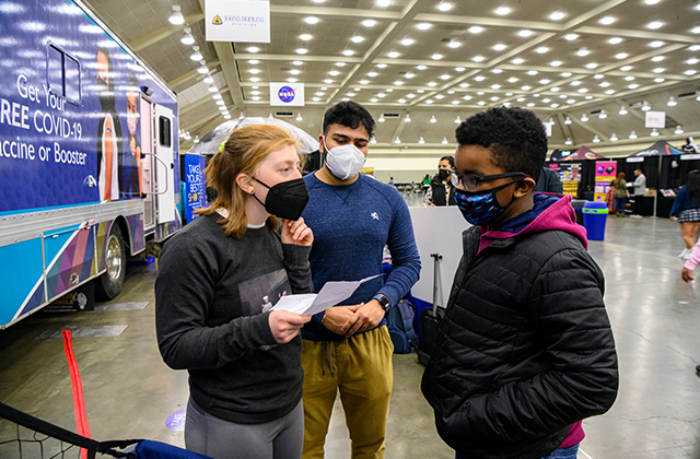 Members of the mobile vaccine team give information to a CIAA Fan Fest attendee.